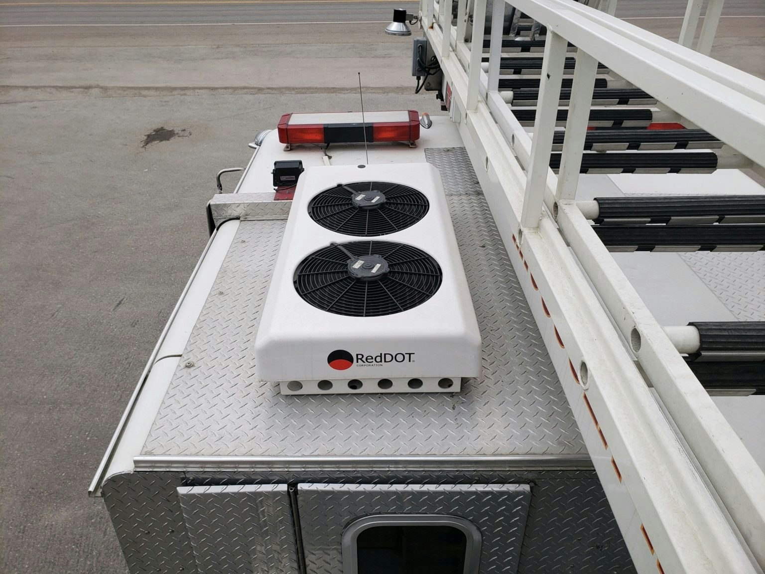 Roof-mounted cooling unit with two fans labeled "RedDOT" on a metal vehicle, possibly an emergency or utility vehicle.