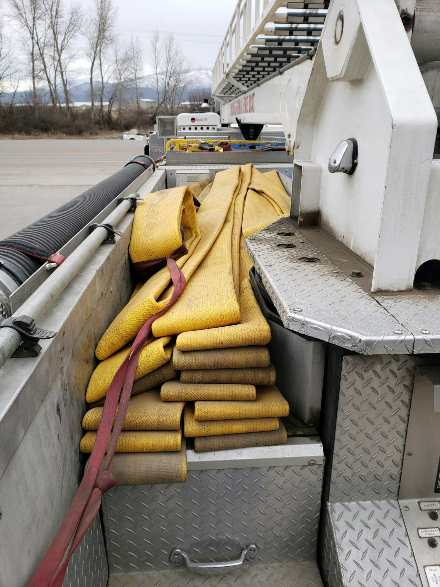 Yellow fire hoses neatly stacked in a truck compartment, with metal surfaces around them.