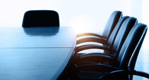 Empty conference table with black chairs in a brightly lit room.