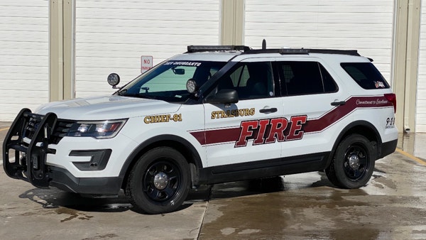A white fire department SUV with "FIRE" and "CHIEF-01" markings, equipped with emergency lights and a front guard.