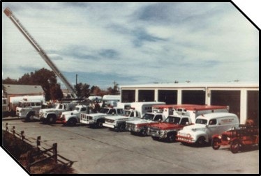 Vintage photo of a fleet of tow trucks in front of a service garage.