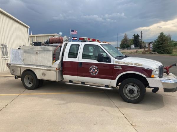 A fire service pickup truck with equipment, parked outside under cloudy skies.