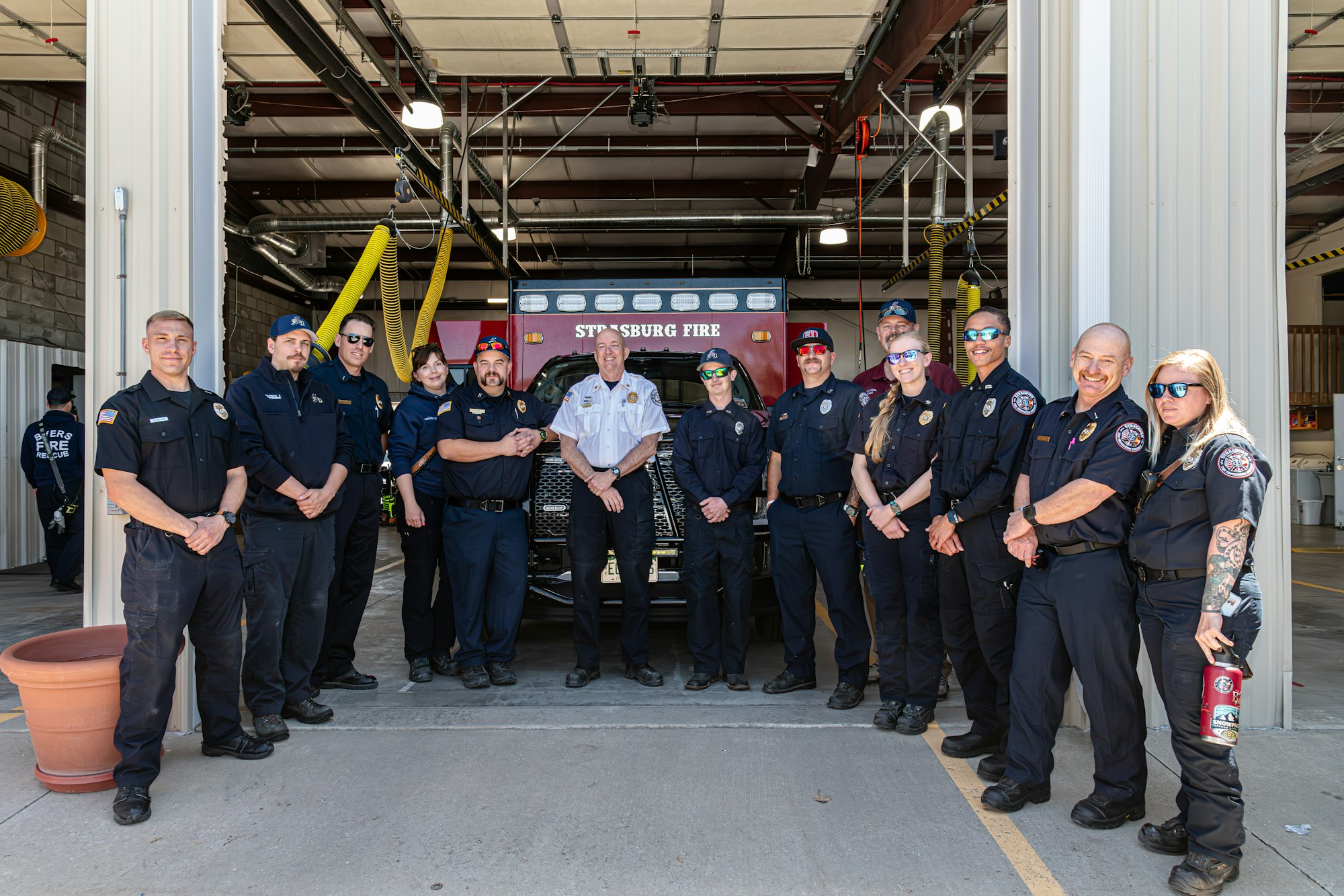 Strasburg Fire Protection District crew standing in front of a fire engine in a station.