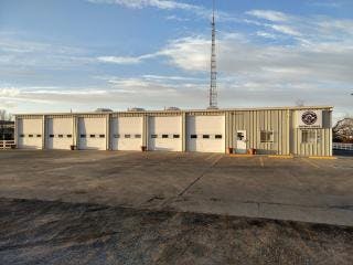 A building with multiple garage doors, a tall antenna, and a clear sky.