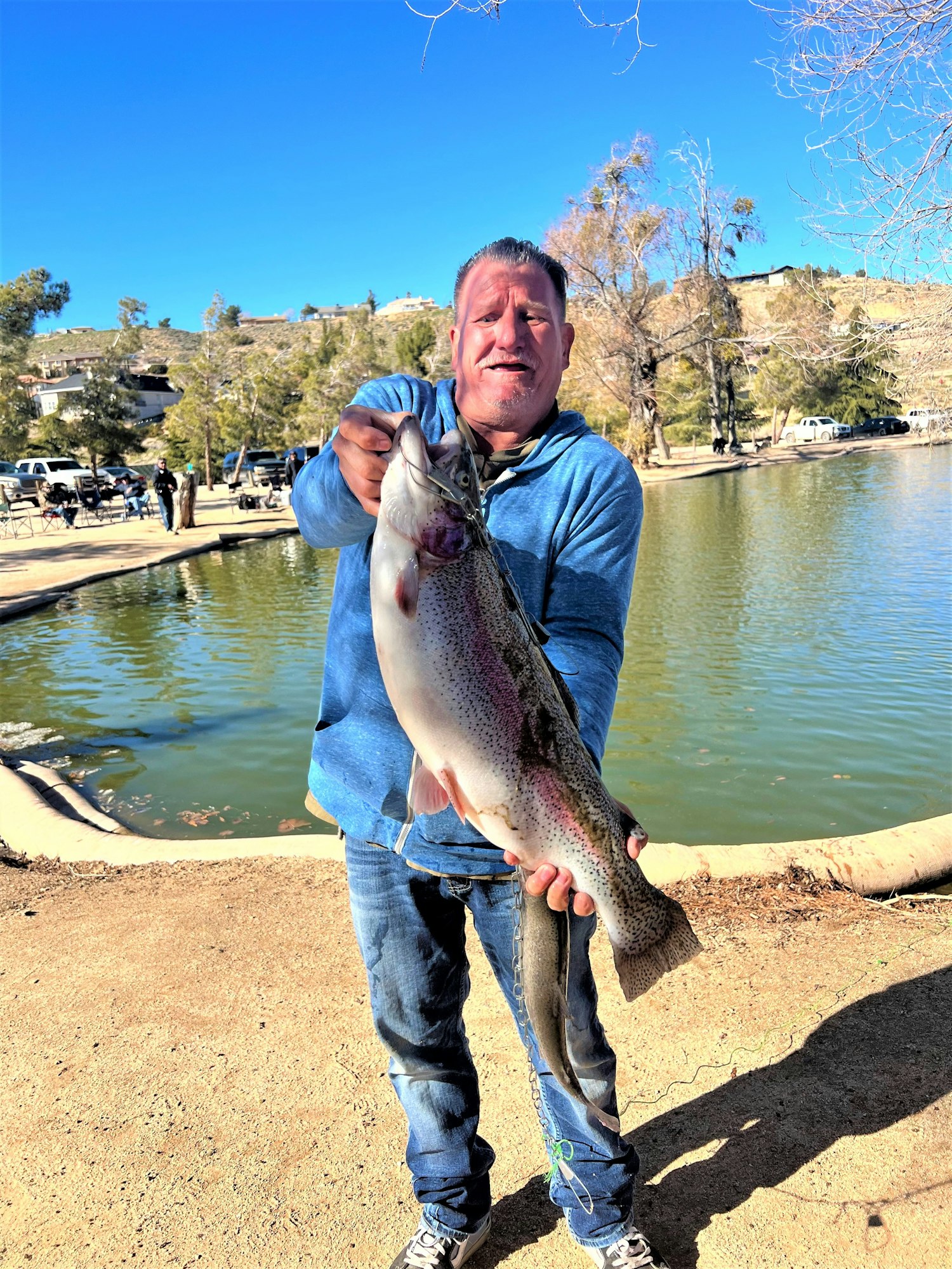 May contain: pants, clothing, portrait, person, photography, head, face, fish, sea life, animal, fishing, water, outdoors, leisure activities, trout, shoe, footwear, jeans, pond, nature, car, vehicle, and transportation