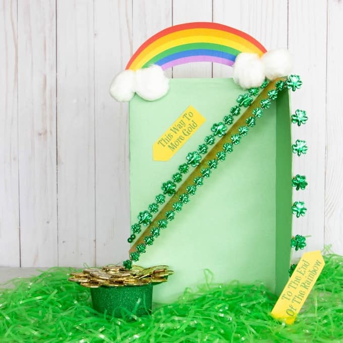 Leprechaun trap with rainbow on top and slide going down into a hat filled with gold coins