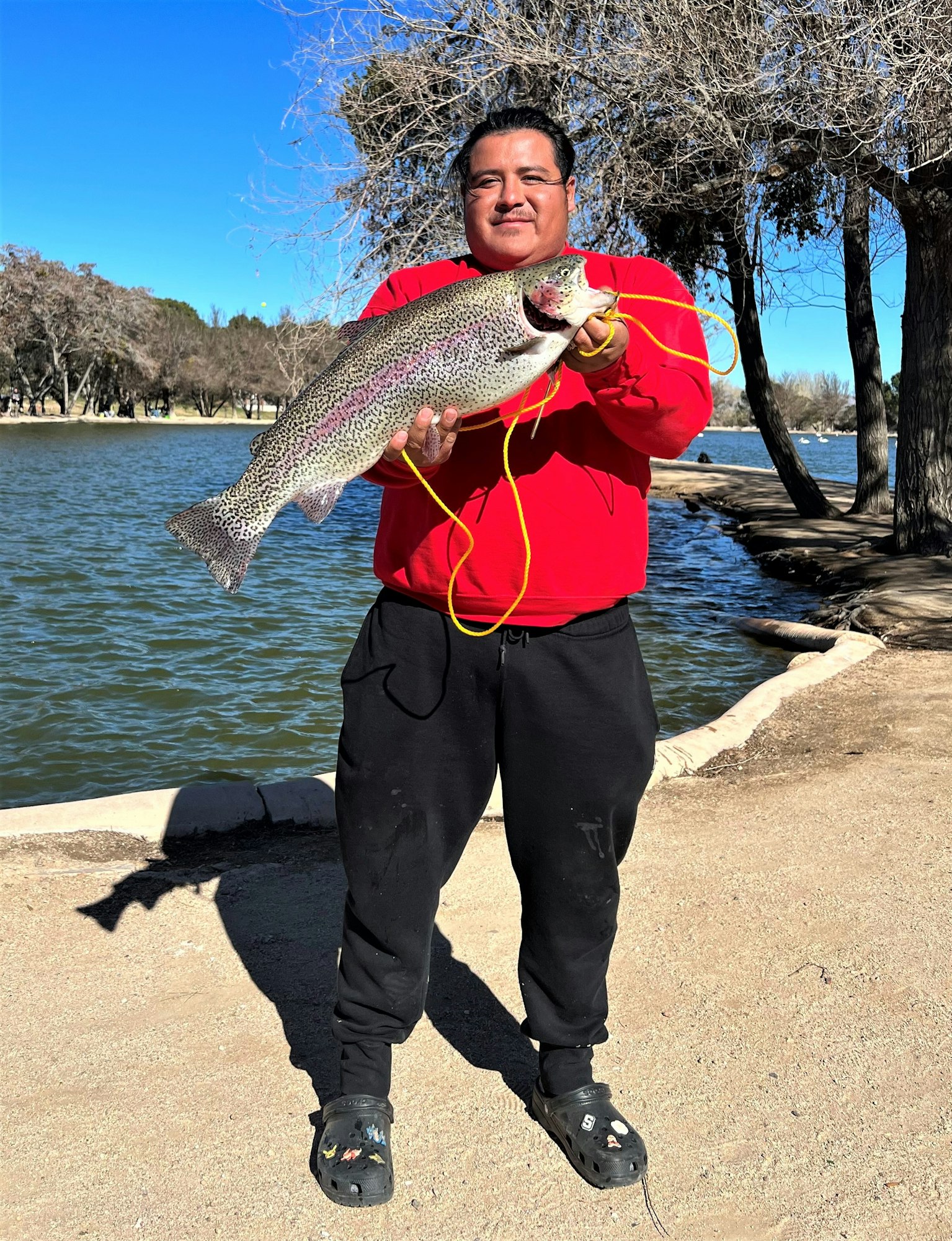 May contain: soil, portrait, photography, person, head, face, trout, fish, sea life, animal, pants, clothing, shoe, footwear, tree, plant, rock, man, adult, male, bonito, tuna, water, outdoors, lake, nature, waterfront, fishing, and leisure activities