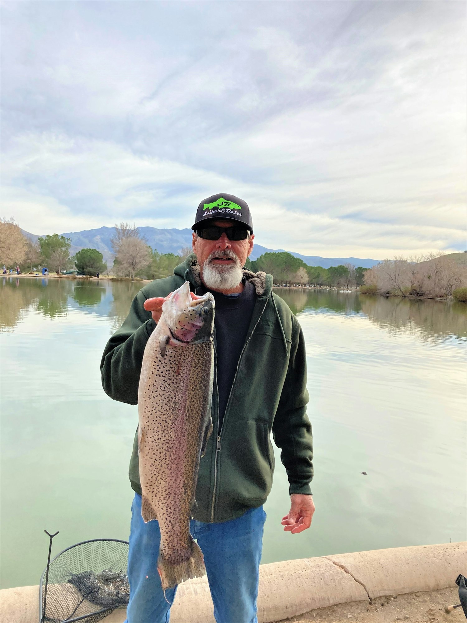 May contain: portrait, photography, person, head, face, fish, sea life, animal, jacket, coat, clothing, pants, outdoors, trout, man, adult, male, fishing, water, leisure activities, lake, nature, glasses, and accessories