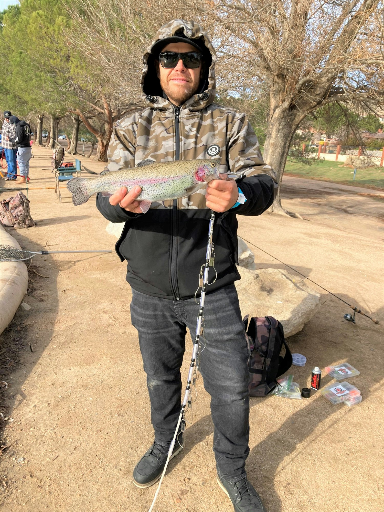 May contain: portrait, photography, person, head, face, jacket, coat, clothing, soil, pants, trout, fish, sea life, animal, sunglasses, accessories, vegetation, plant, tree, park, grass, outdoors, nature, glasses, rock, shoe, and footwear