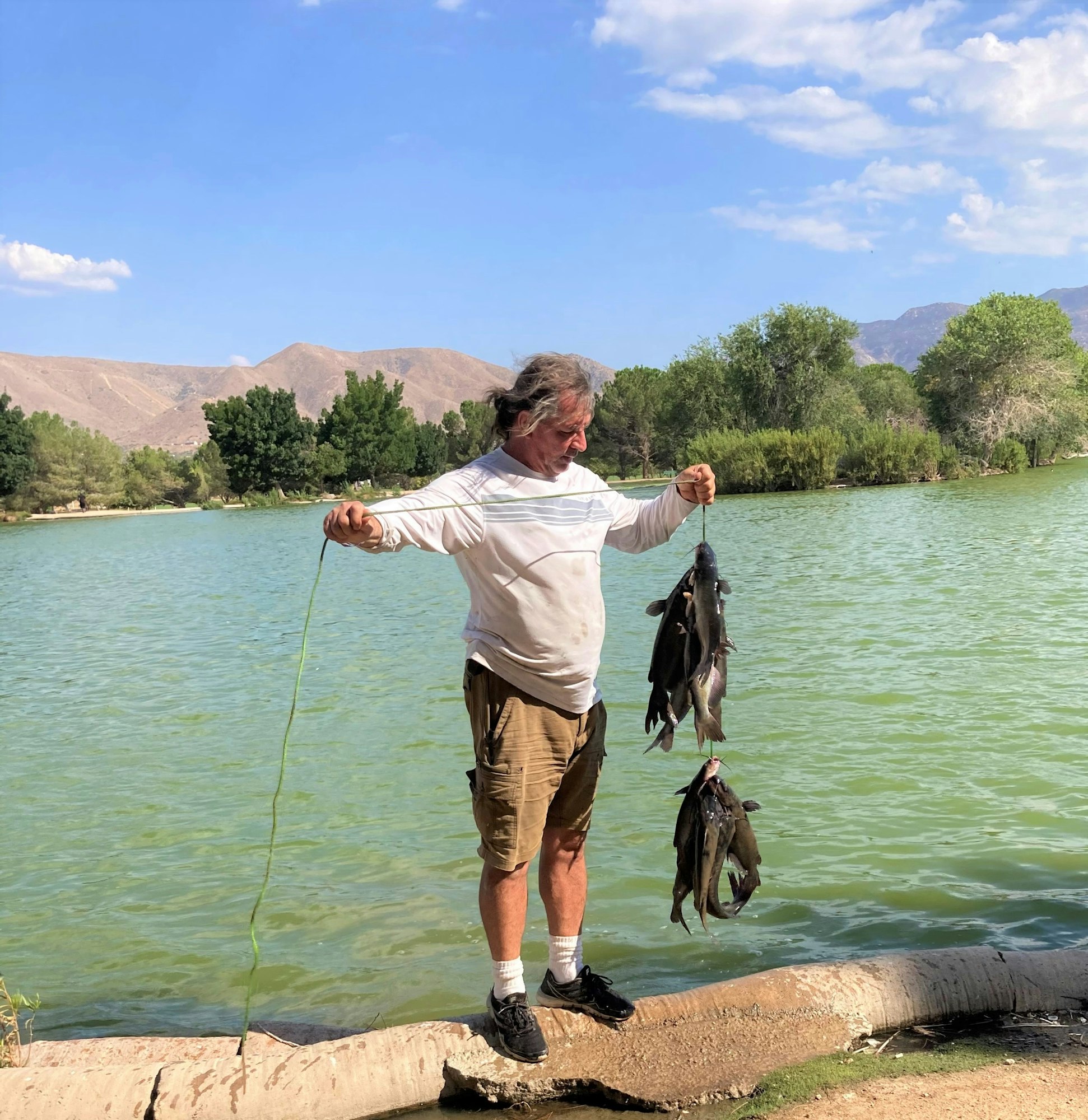 May contain: water, outdoors, person, human, fishing, shorts, clothing, and apparel
