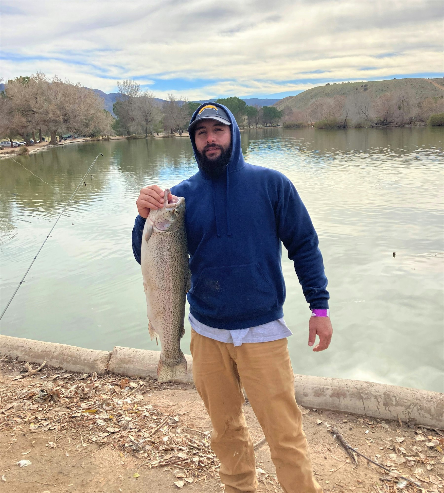 May contain: portrait, photography, person, head, face, pants, clothing, fishing, outdoors, water, leisure activities, soil, man, adult, male, fish, sea life, animal, hoodie, sweatshirt, sweater, knitwear, trout, jacket, coat, lake, and nature