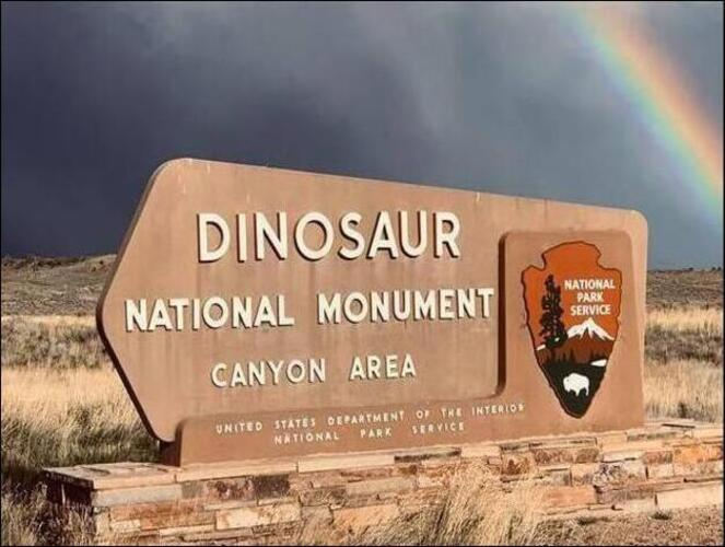 Sign for Dinosaur National Monument Canyon Area with a rainbow in the background.