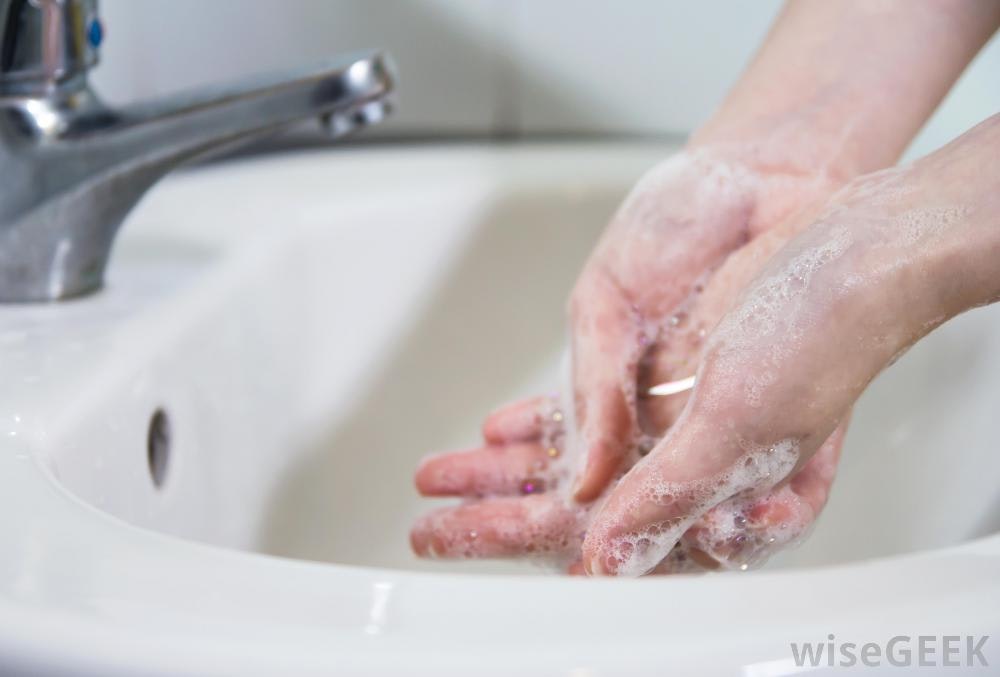 Hands being washed with soap at a sink.