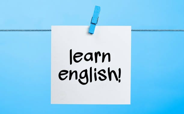 A note reading "learn english!" is clipped on a line with a blue clothespin against a blue background.