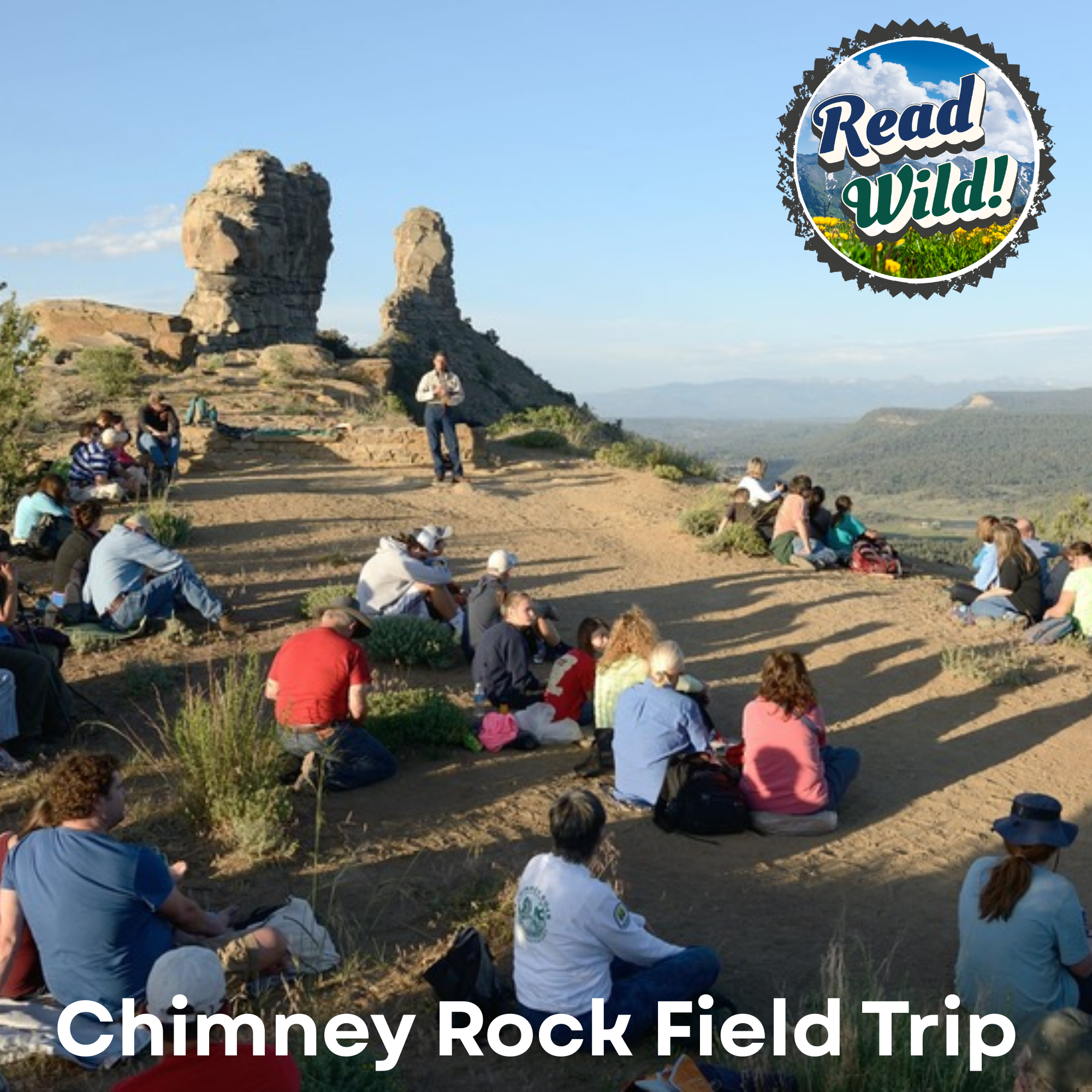 A group of people attends a field trip at Chimney Rock, listening to a speaker against a scenic backdrop.