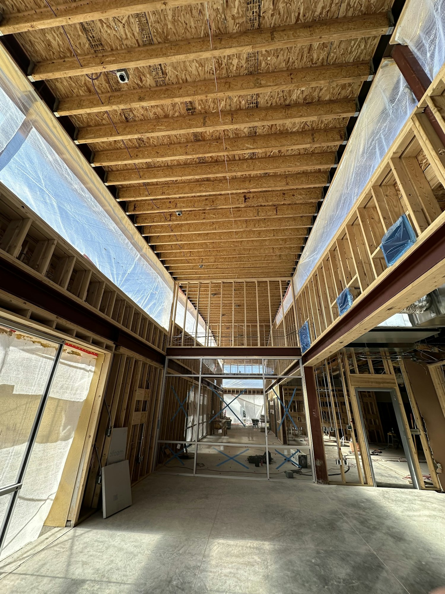 The image shows an unfinished interior space with wooden beams, framing, and construction materials, indicating ongoing building work.