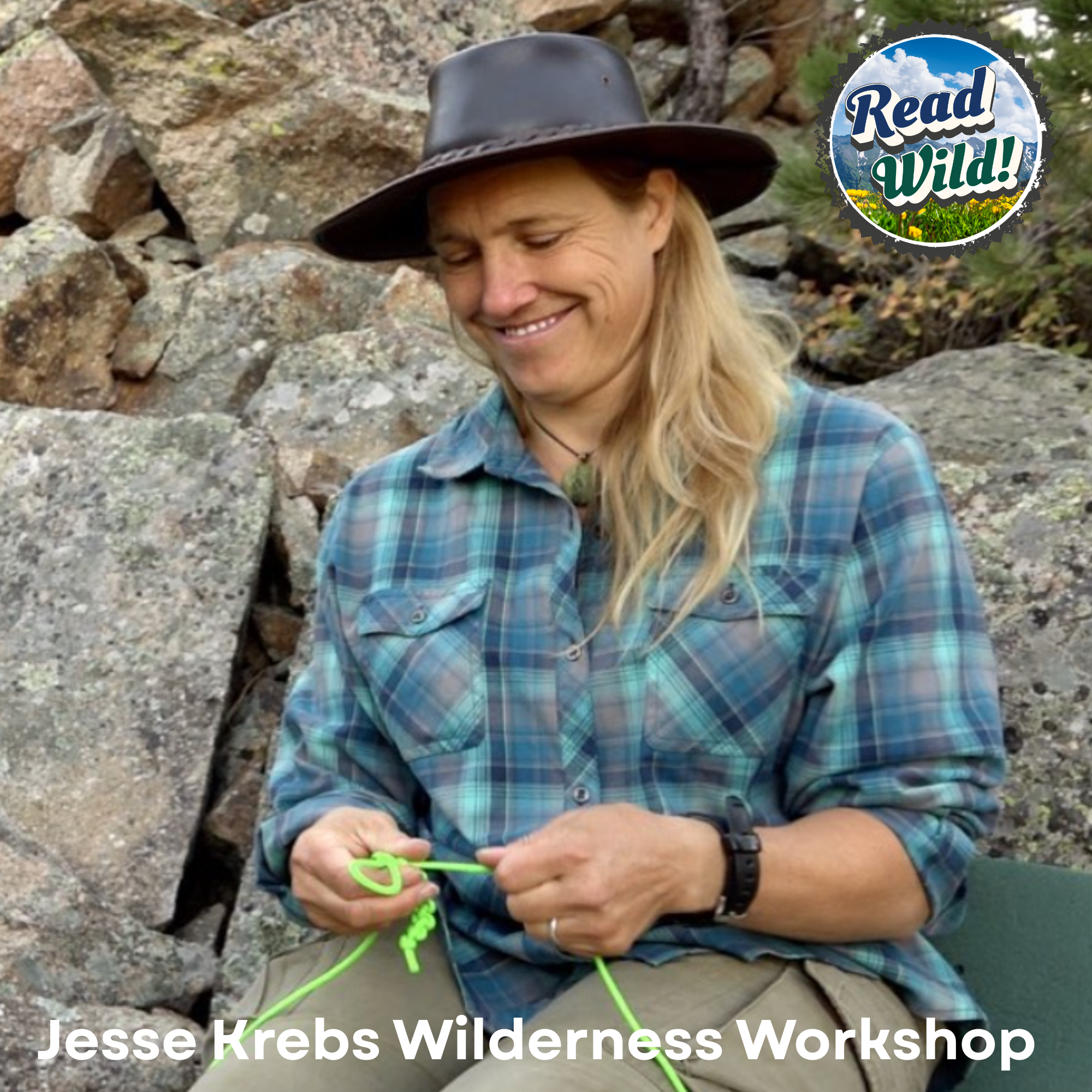 A person is engaged in a wilderness workshop, smiling while working with green cordage among rocky surroundings.