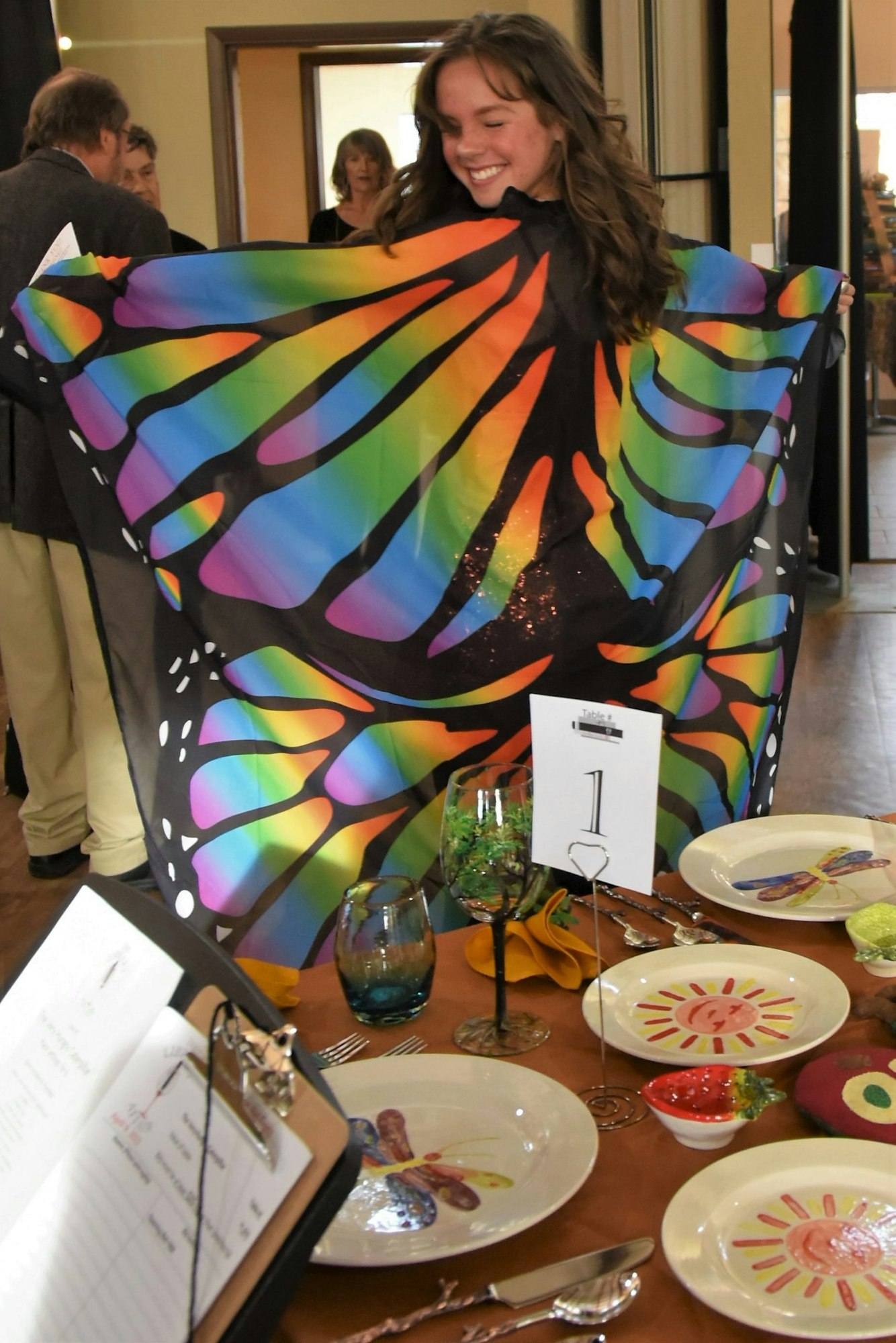 May contain: dining table, furniture, table, architecture, building, dining room, indoors, room, food, meal, face, head, person, photography, portrait, cutlery, adult, female, woman, dish, glass, clothing, footwear, shoe, dress, fork, plate, cup, and formal wear