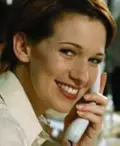 A smiling woman holding a phone to her ear.
