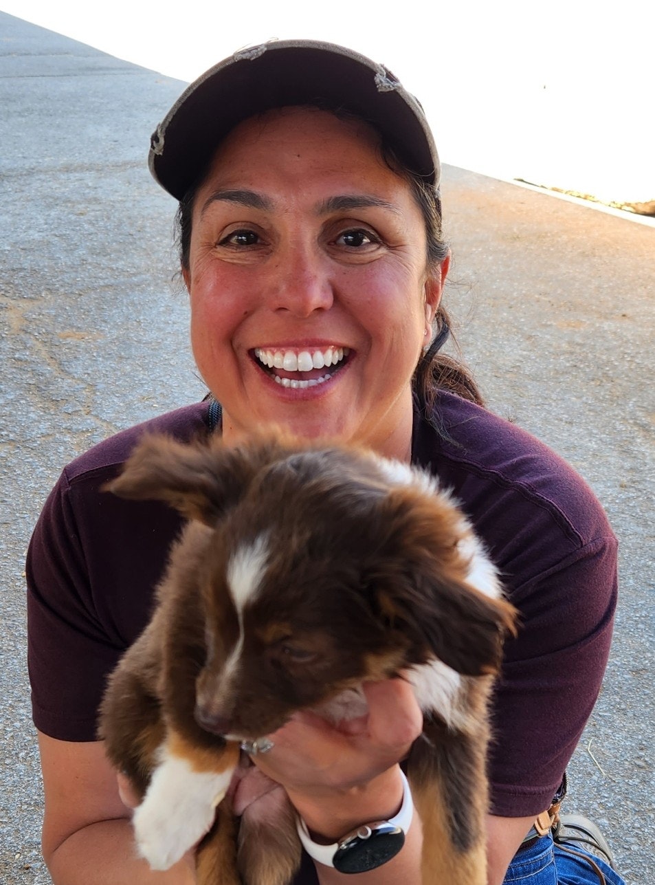 A person smiling and holding a fluffy puppy.