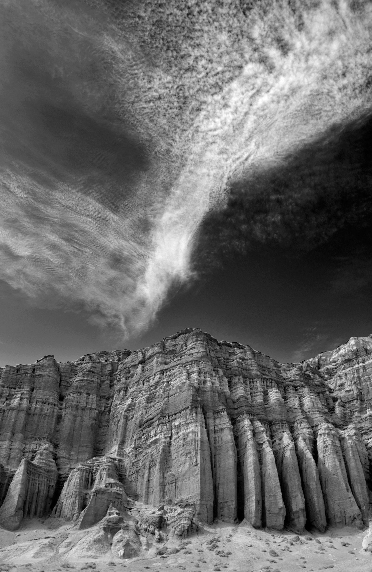Dramatic clouds over towering rock formations, captured in black and white.