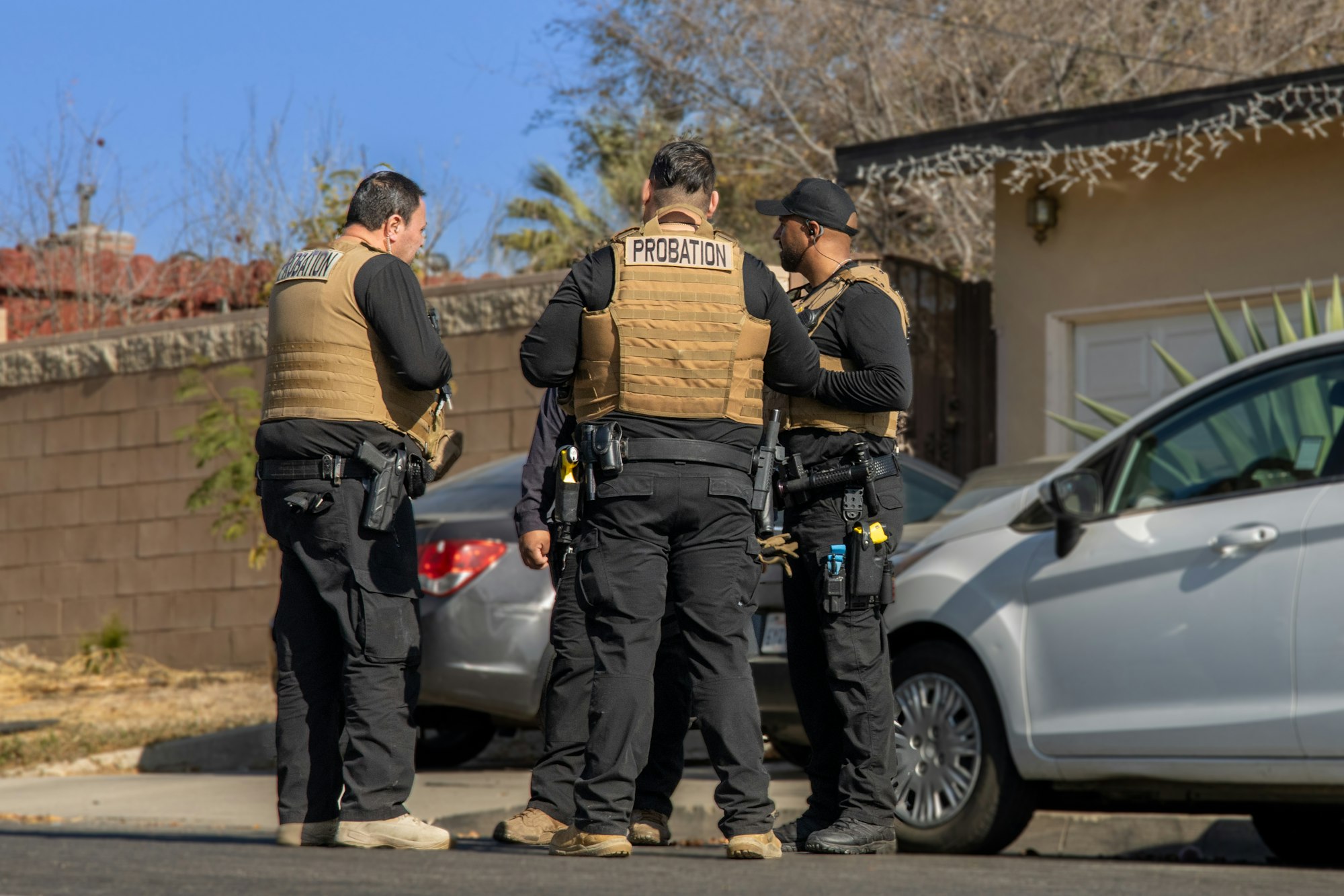 Three probation officers in tactical gear on a sunny street.