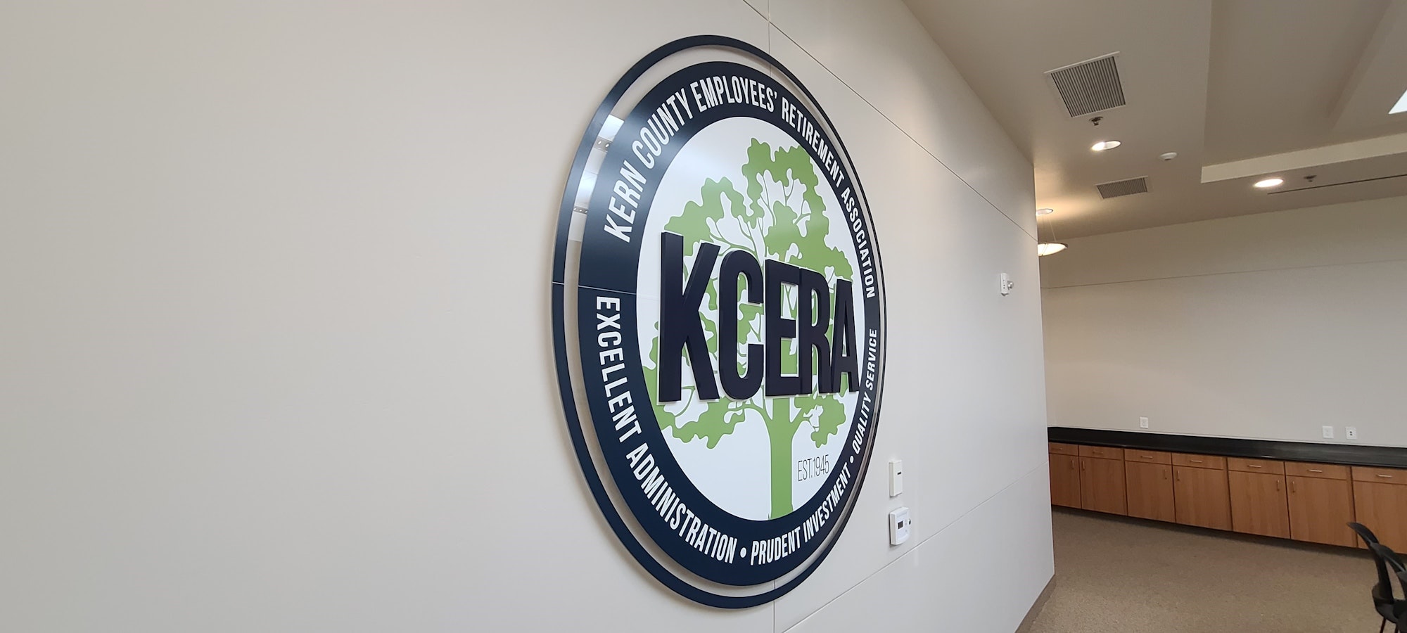 A wall-mounted emblem for the Kern County Employees' Retirement Association (KCERA) in an office setting.