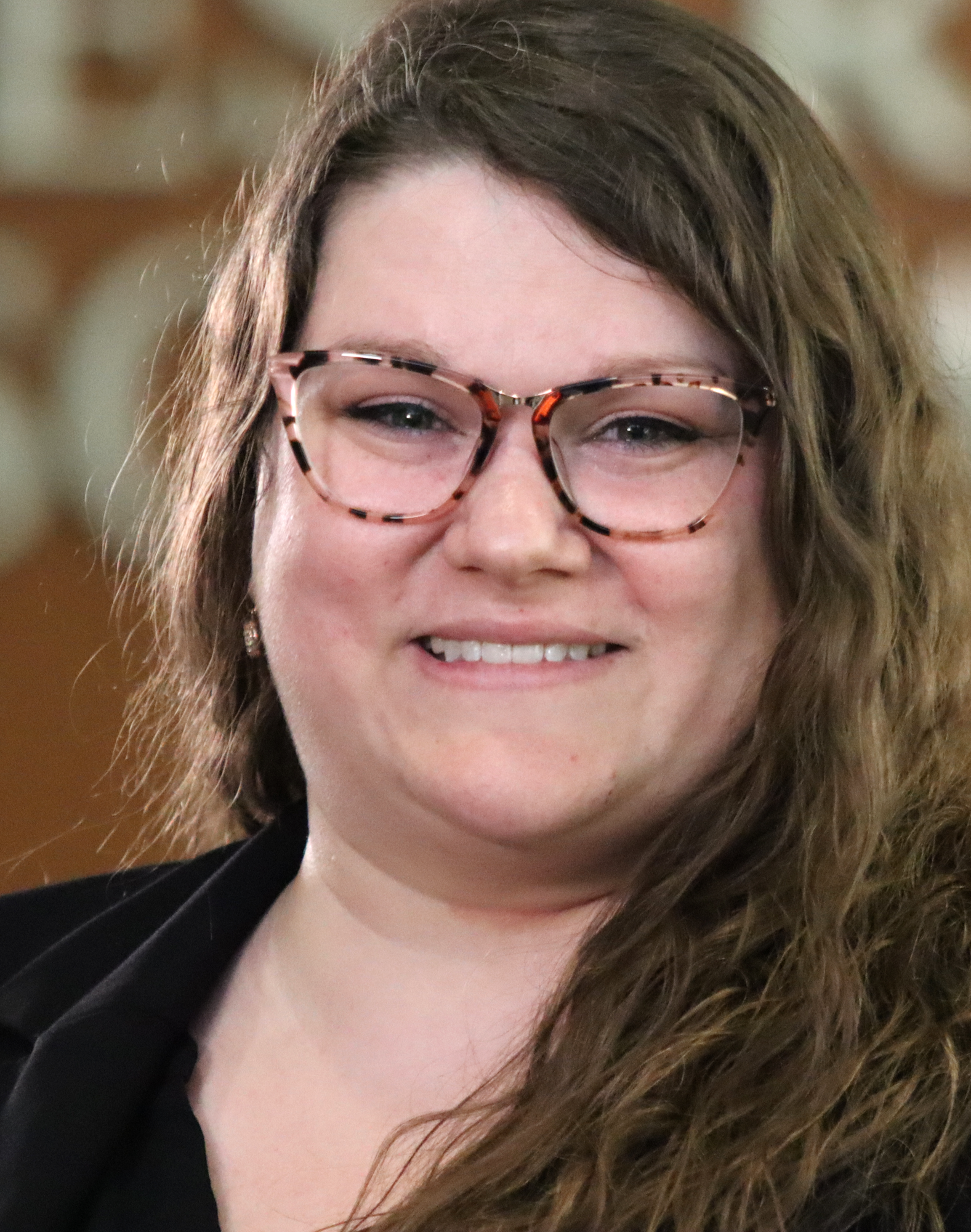 A smiling woman with glasses and long hair.