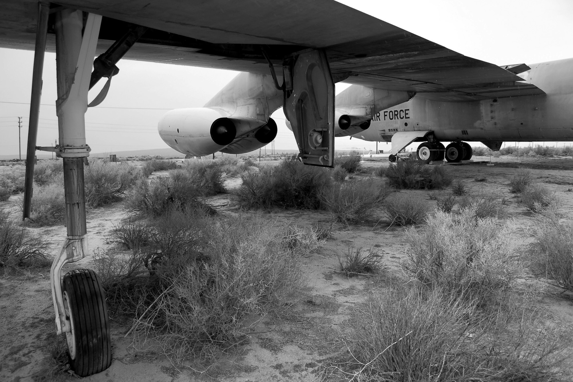 Part of a decommissioned Air Force plane sitting in a desert landscape, seen in black and white.