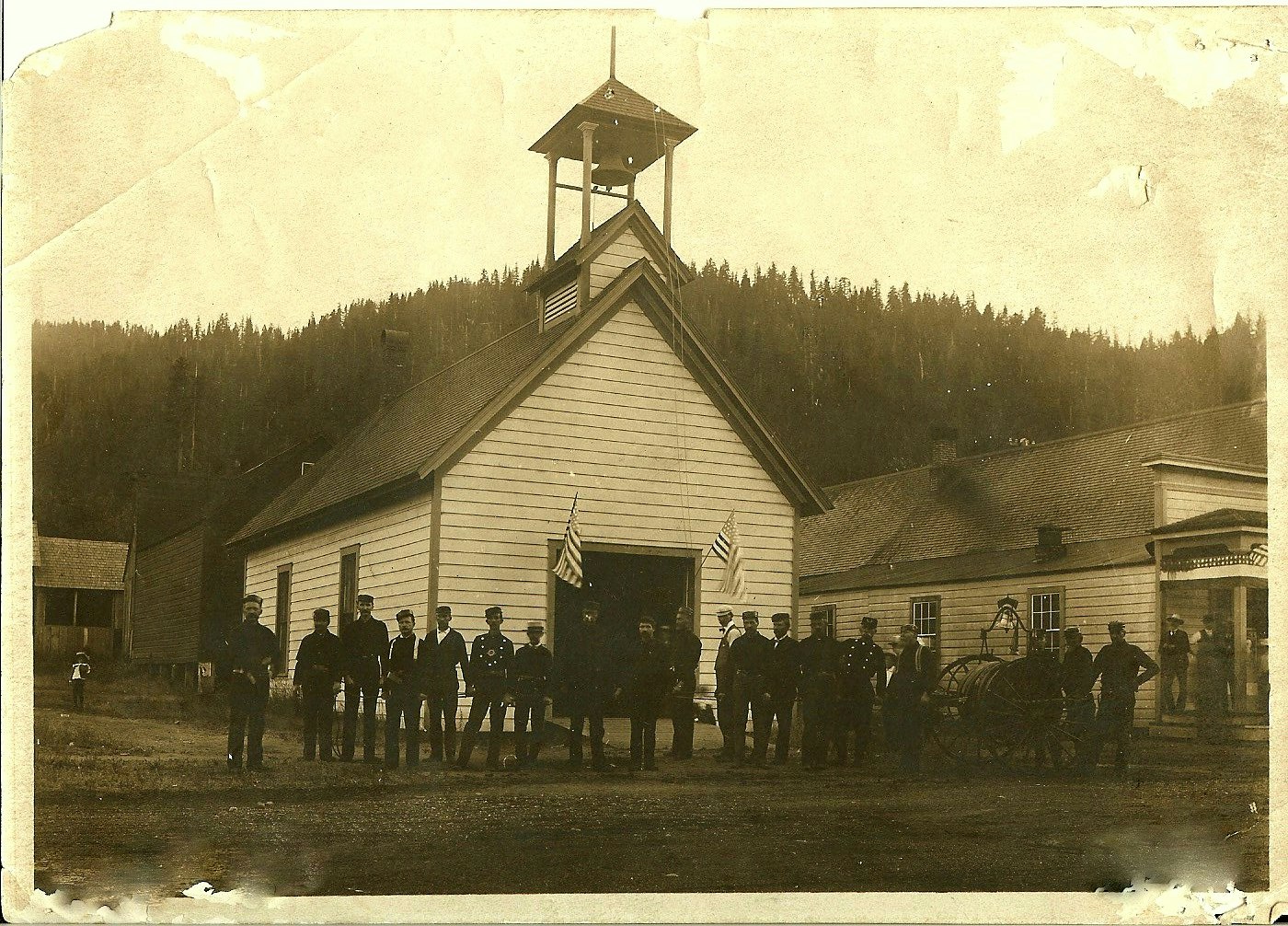 A sepia-toned photo of Main Street station in late 1800s people standing in front of Quincy Hose No. 1 fire station