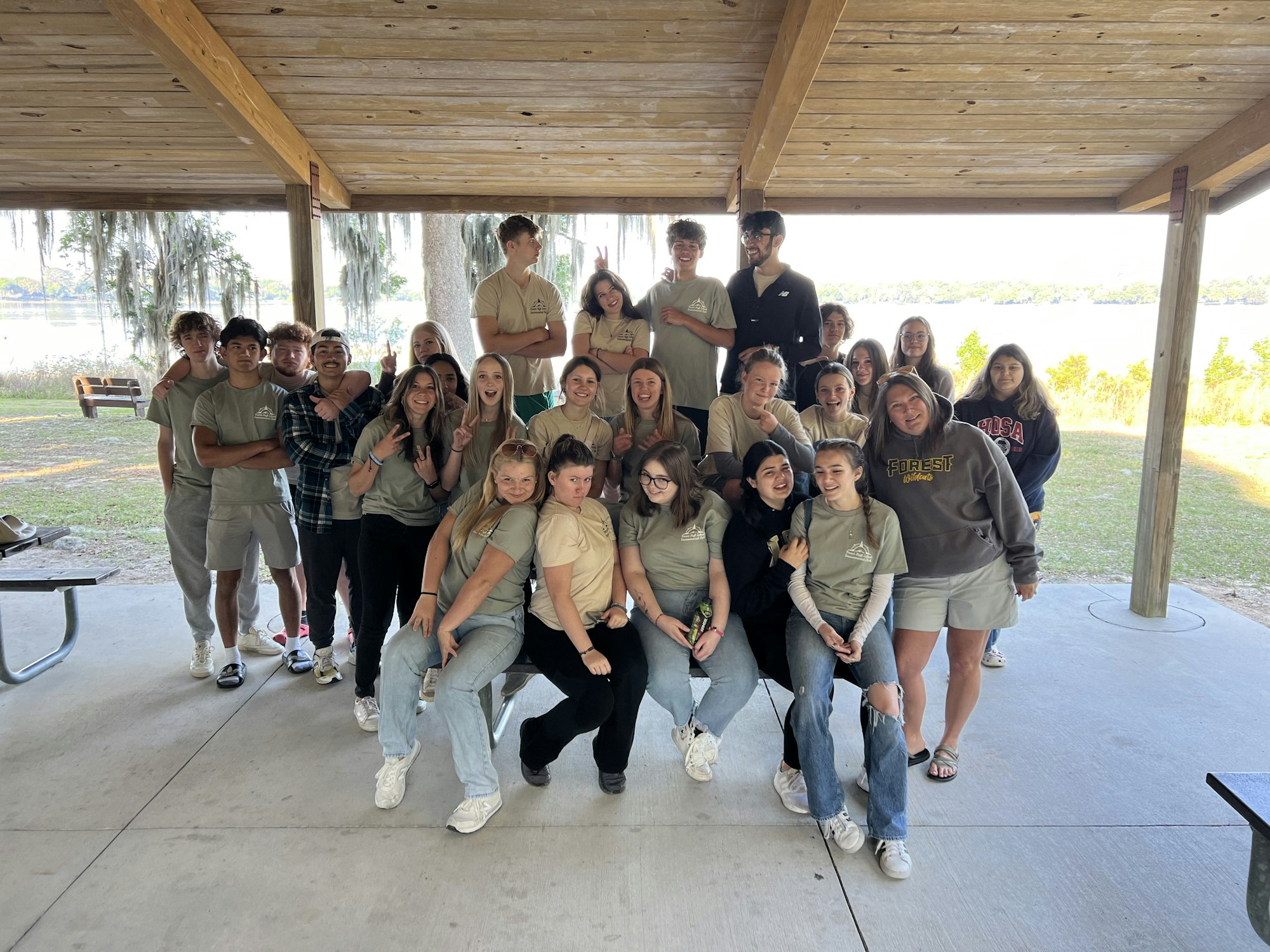 A group of happy people posing together outdoors under a shelter.