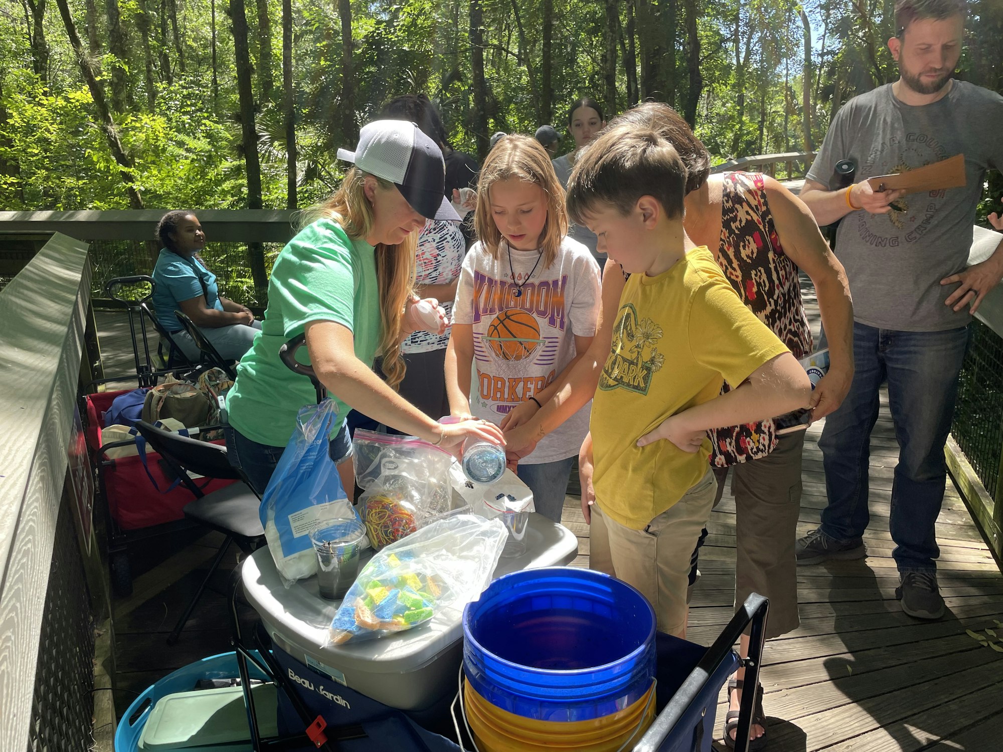 People gathered around supplies on a sunny day, possibly during an outdoor activity or event.