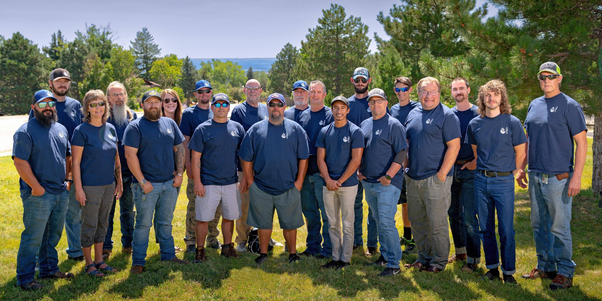 A group of people in matching blue shirts posing outdoors.