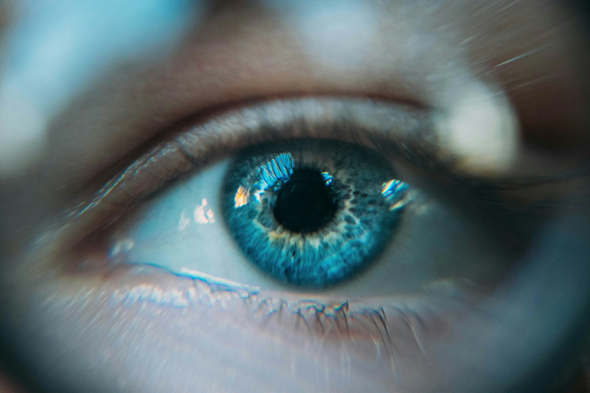 Close-up of a blue eye with intricate iris details and reflections.