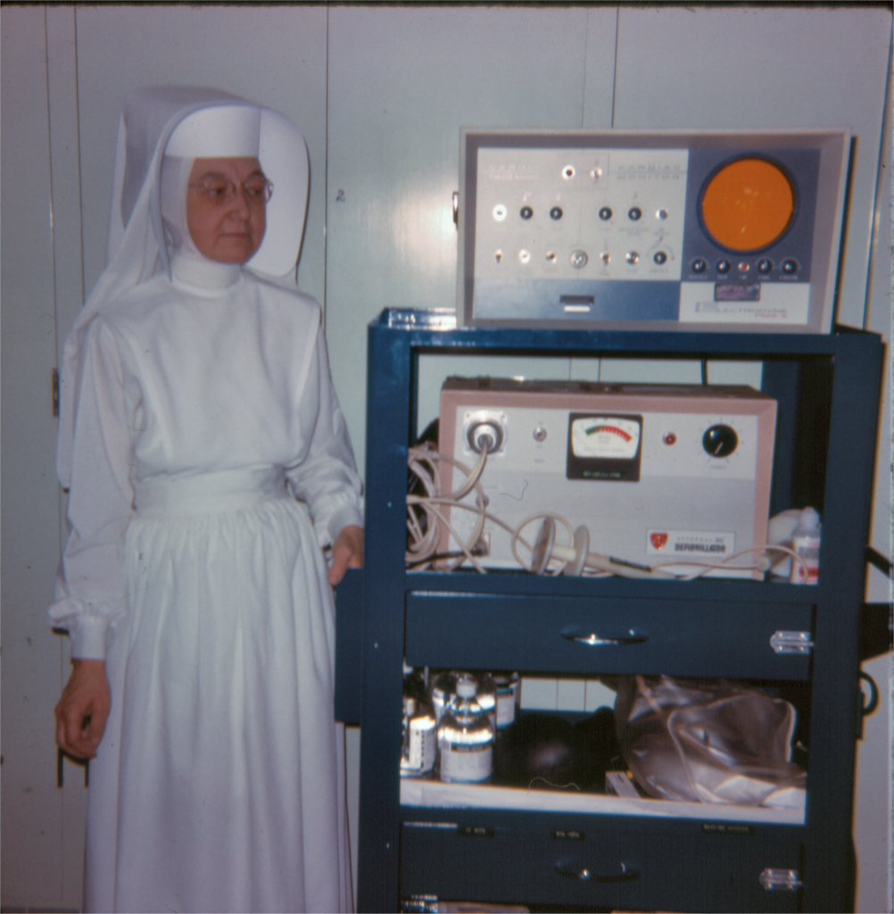A person in a nun's habit standing next to medical equipment.