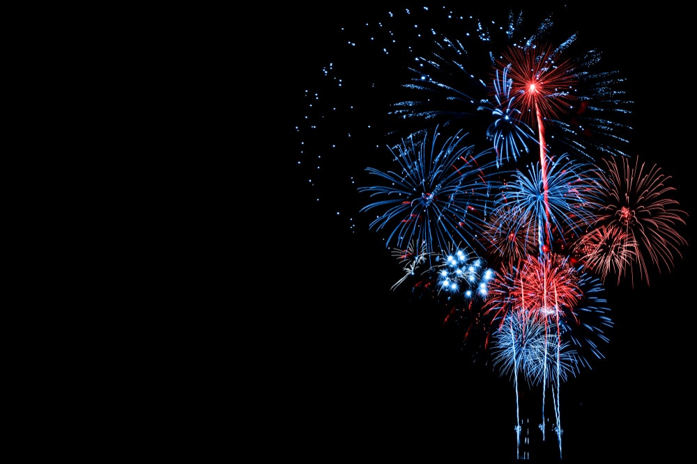 Red and blue fireworks burst against a black sky with streaks and sparkles in various patterns.