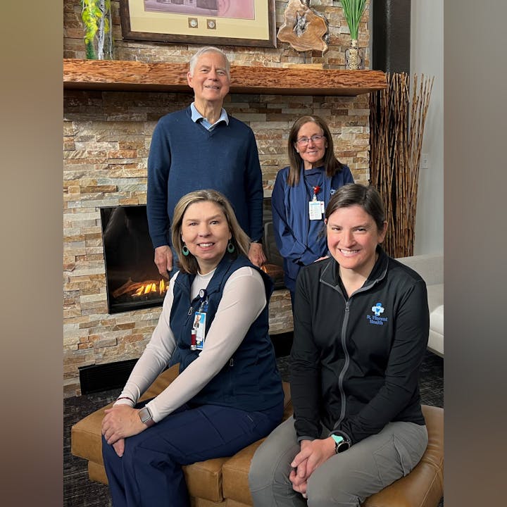 Four people smiling for a group photo in front of a fireplace.
