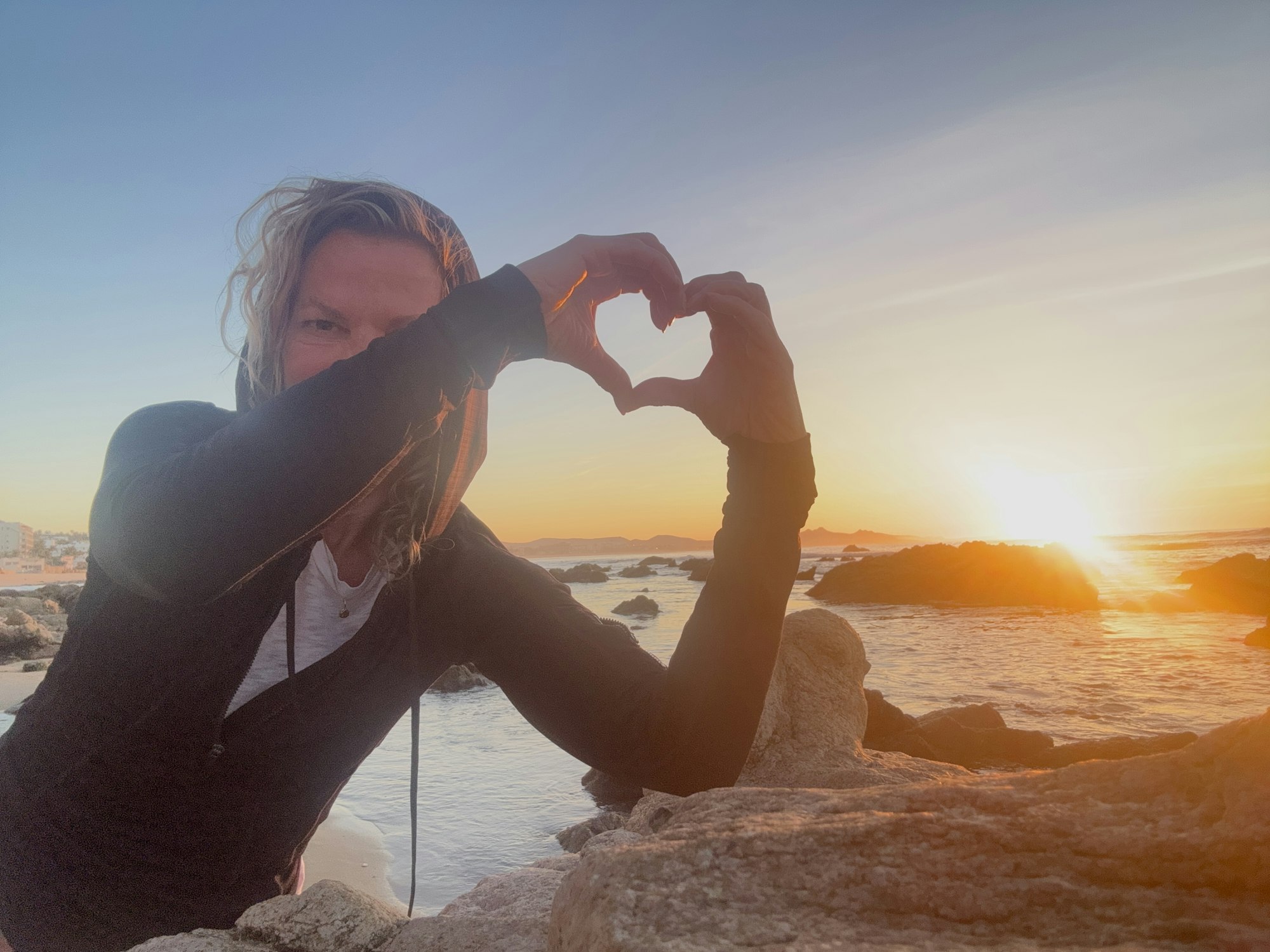 Dr. Stilp at an alpine lake making a heart shape with hands at sunset.