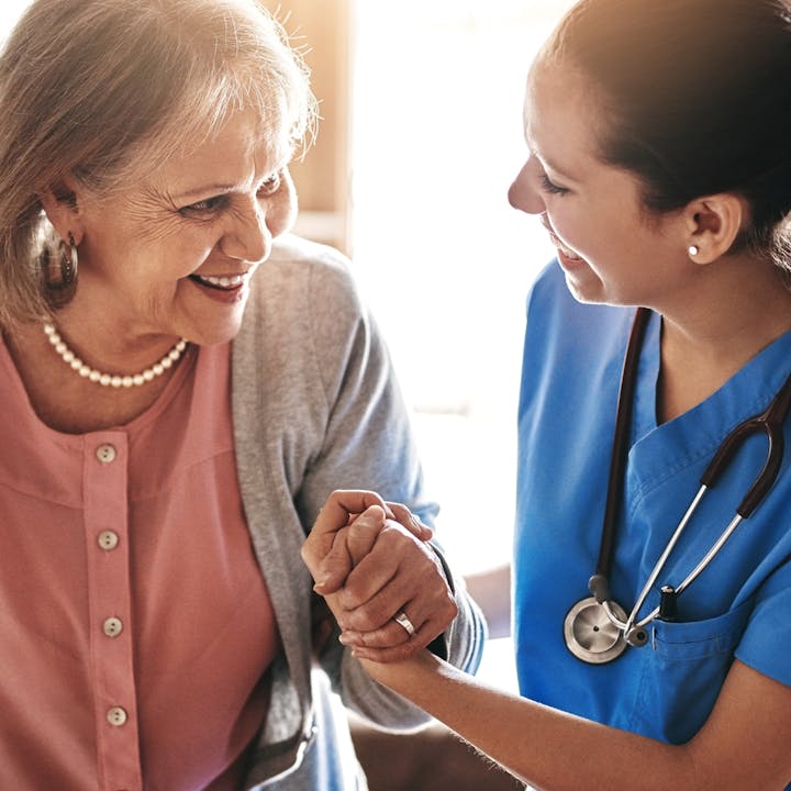 A joyful interaction between an elderly woman and a caregiver, sharing a warm moment of connection and support.
