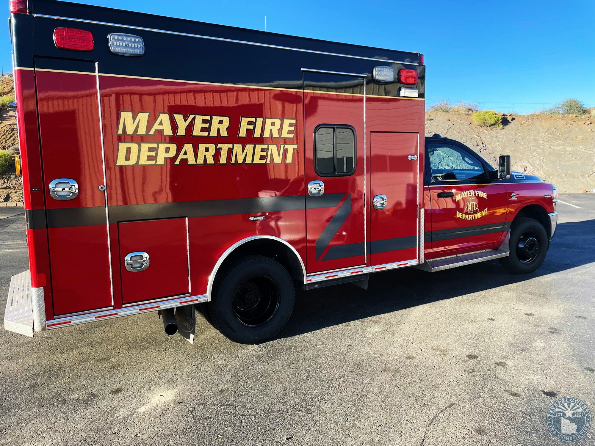 A red Mayer Fire Department vehicle parked on asphalt, with clear blue sky in the background.