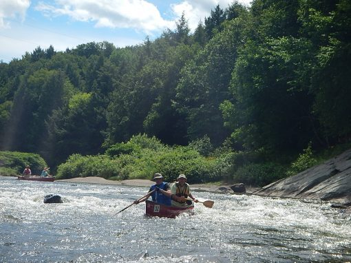 May contain: boat, transportation, vehicle, person, canoe, canoeing, leisure activities, rowboat, sport, water, water sports, plant, vegetation, clothing, hat, adventure, and rafting