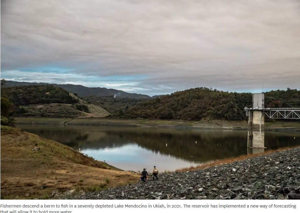 Fishermen at a depleted Lake Mendocino, Ukiah. Hilly landscape and cloudy sky in the background.