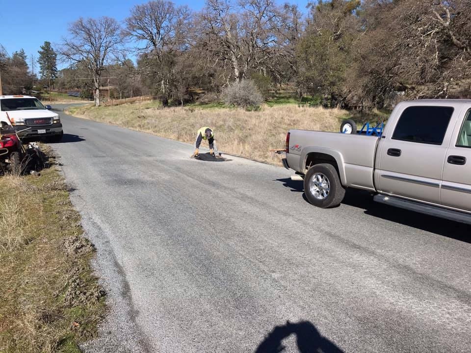 man patching road with trucks
