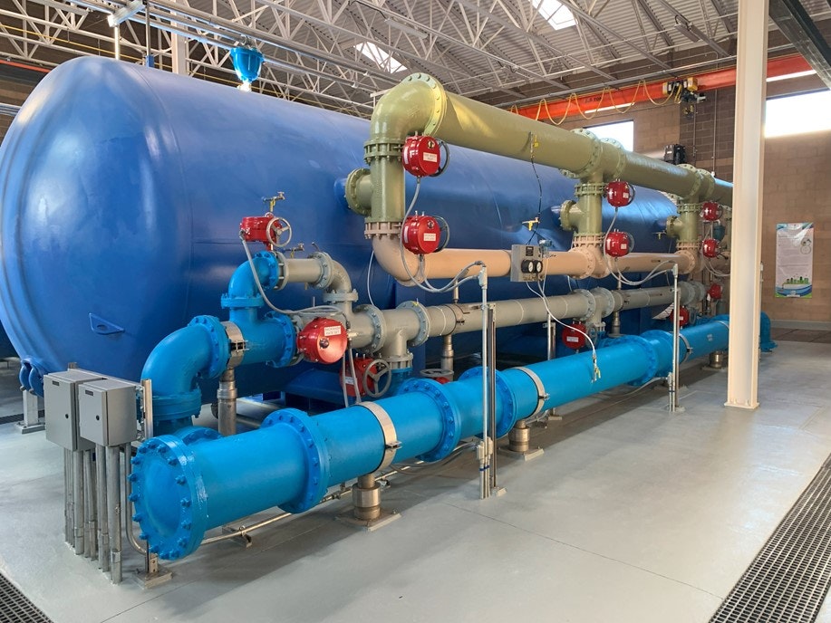 Industrial water treatment equipment with large blue pipes and tanks.