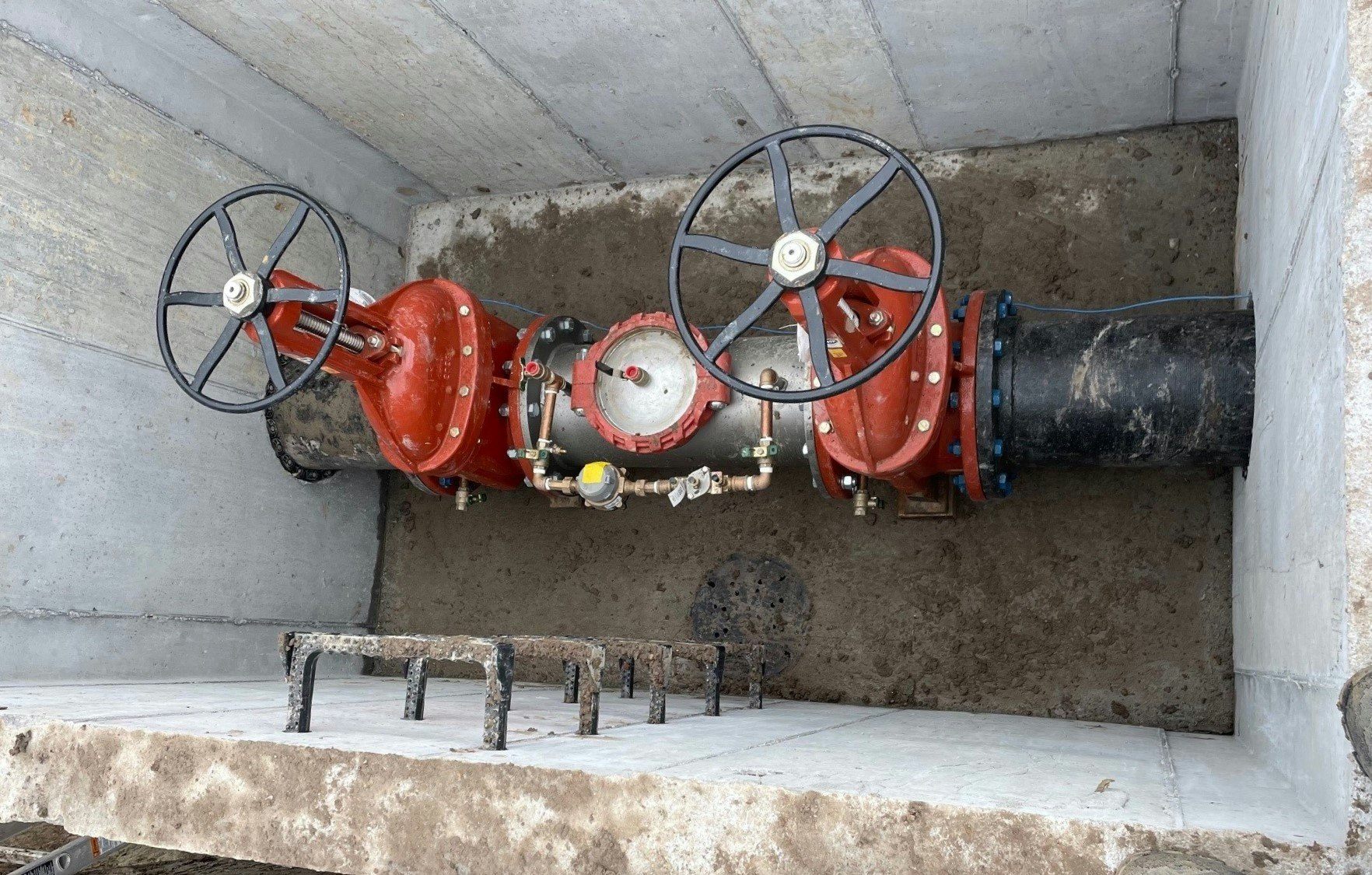 Industrial valves and piping in a concrete chamber.