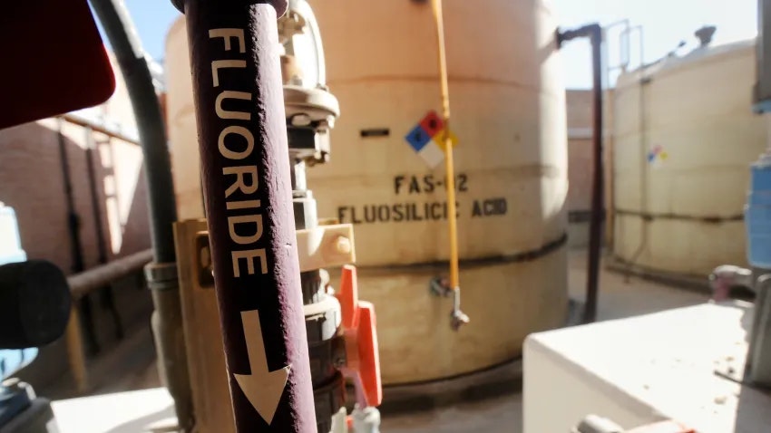 Industrial tanks labeled "Fluosilicic Acid" with pipes marked "Fluoride" in a processing facility.