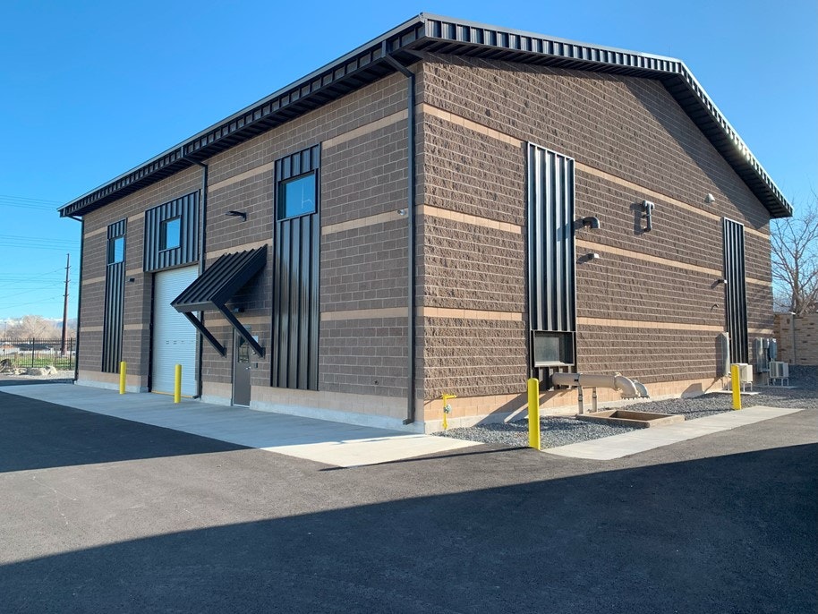 A modern brick building with large windows, a metal awning, and a clear blue sky.