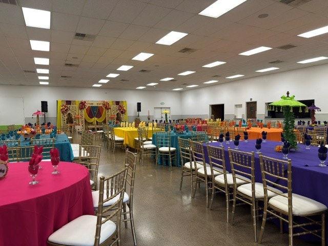 A vibrant event space with colorful tables, decorations, and chairs, set up for a festive gathering or celebration.