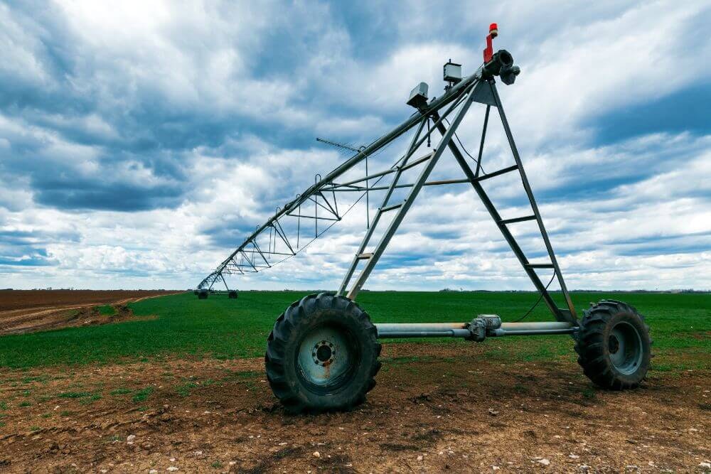 A large irrigation pivot system in a field under a cloudy sky.