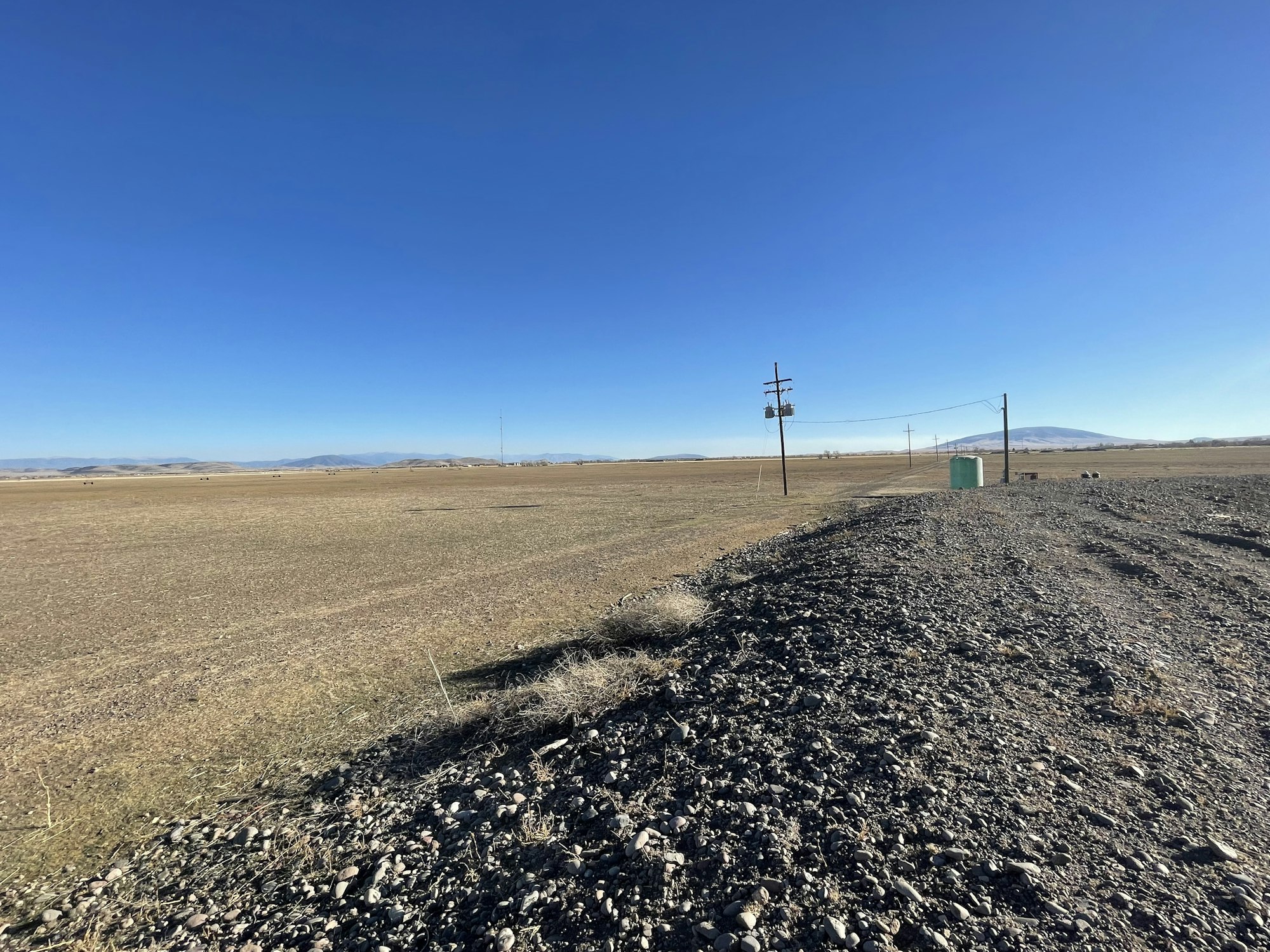 May contain: ground, gravel, road, horizon, nature, outdoors, sky, utility pole, and scenery